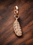 Rose Gold Plated Feather Charm - Rose Gold Plated Feather Dangle Charm — display on walnut