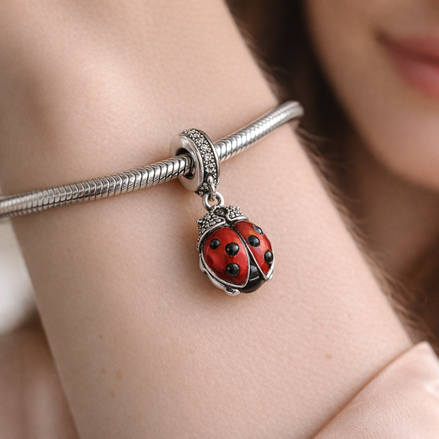 Red Ladybird Dangle Charm — worn on wrist