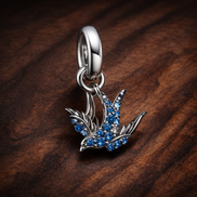 Blue Bird Charm - Silver Bird with Blue Crystal Charm — display on walnut