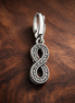 Infinity Charm - Sparkling Infinity Dangle Charm — display on walnut