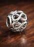Openwork Infinity Charm — display on walnut