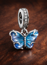 Blue Murano Glass Butterfly Dangle Charm — display on walnut