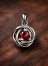 Red Eternity Circle Dangle Charm — display on walnut