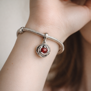 Red Eternity Circle Dangle Charm — worn on wrist