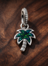Opalescent Green Palm Tree Dangle Charm — display on walnut