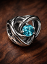 Entwined Heart Charm for UNICEF — display on walnut
