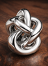 Infinity Knot Charm — display on walnut