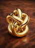 Infinity Knot Charm — display on walnut