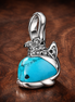 Turquoise-colored Whale Dangle Charm — display on walnut