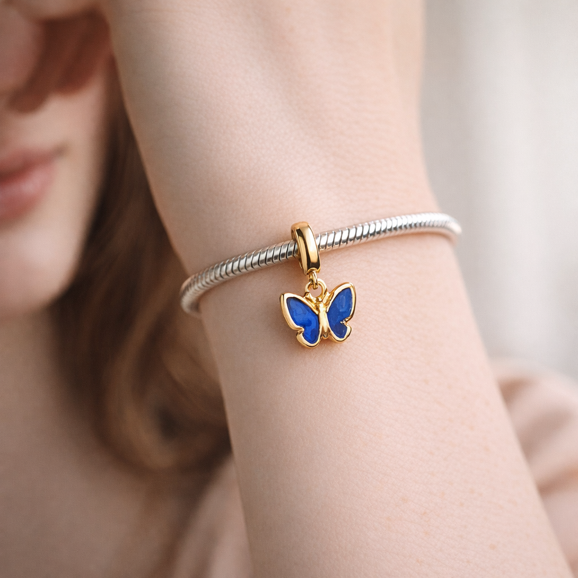 Blue Butterfly Mini Dangle Charm — worn on wrist