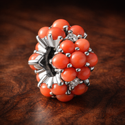 Coral-colored Ocean Charm — display on walnut