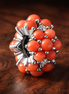 Coral-colored Ocean Charm — display on walnut