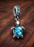 Murano Glass Sea Turtle Dangle Charm — display on walnut
