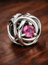 October Pink Eternity Circle Charm — display on walnut